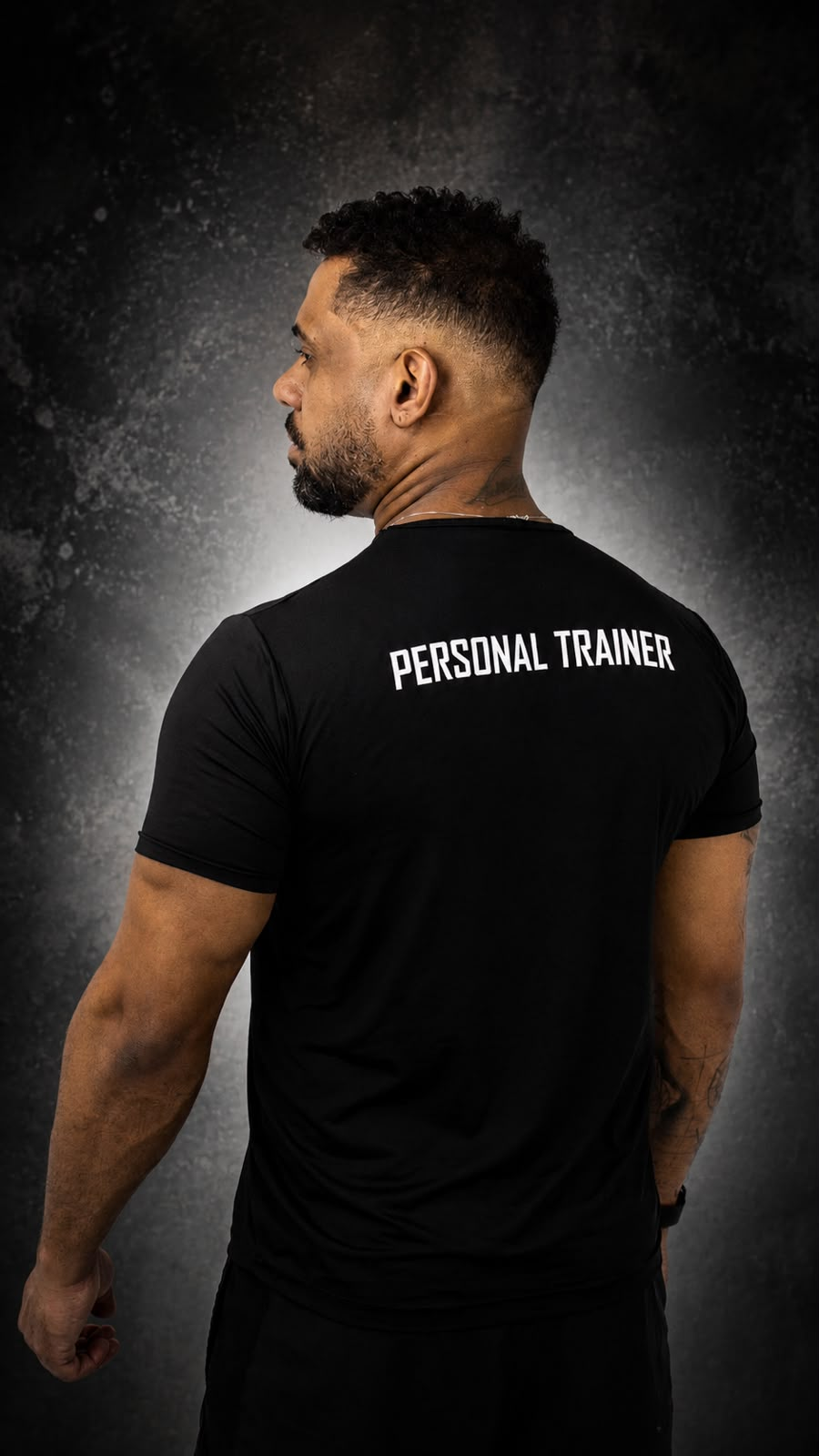Jeferson Leal de costas, com PERSONAL TRAINER escrito na camiseta